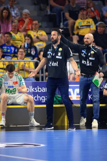 Bennet Wiegert, head coach of SC Magdeburg, gesticulates passionately on the touchline during the DAIKIN HBL match in the SAP Arena Next to him stands a coach with a tactics board, while a player in a white SCM jersey sits exhausted on the bench SC Magdeburg coach Bennet Wiegert gives instructions on the touchline in the SAP Arena Copyright: xspeedshotx