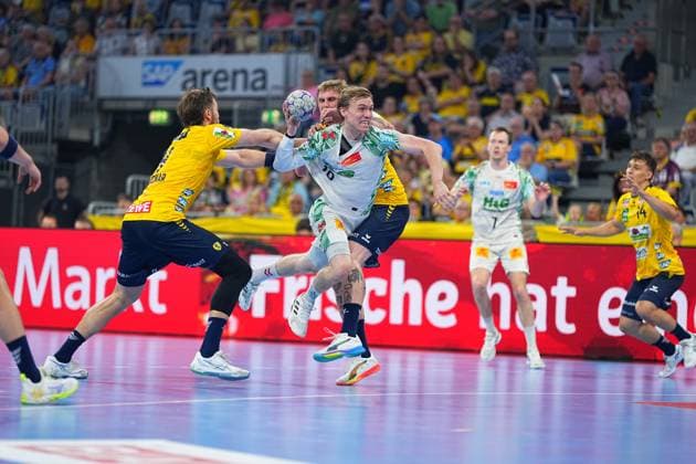 A player of SC Magdeburg 10, white jersey fights his way through under strong pressure from two Rhein Neckar Löwen defenders and pulls away for a shot Gino Steenaerts 14, Rhein Neckar Löwen is seen on the right SC Magdeburg 10 breaks through Löwen cover in the SAP Arena Copyright: xspeedshotx