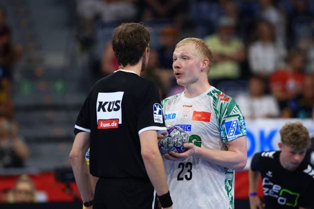 Magnus Saugstrup 23, SC Magdeburg holding the match ball and talking to a referee in the SAP Arena Spectators and another player can be seen in the background Magnus Saugstrup 23 SC Magdeburg talking to a referee Copyright: xspeedshotx