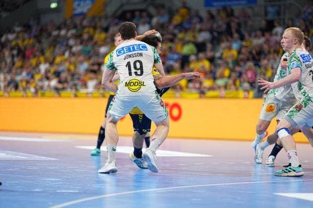 Elvar Örn Jonsson 19 SC Magdeburg in white jersey battles for the ball against a Löwen player in yellow jersey Magnus Saugstrup 23 SC Magdeburg can be seen in the background, while the packed SAP Arena lights up in yellow Elvar Örn Jonsson 19 SC Magdeburg in a duel in the SAP Arena Copyright: xspeedshotx