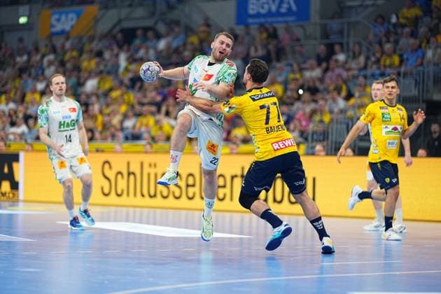 A player of SC Magdeburg with the jersey number 22 jumps for a throw in the SAP Arena and is blocked by Dani Baijens 77, Rhein Neckar Löwen In the background you can see Omar Ingi Magnusson 14, SC Magdeburg and Gino Steenaerts 14, Rhein Neckar Löwen Duel SC Magdeburg 22 against Dani Baijens 77 Rhein Neckar Löwen Copyright: xspeedshotx