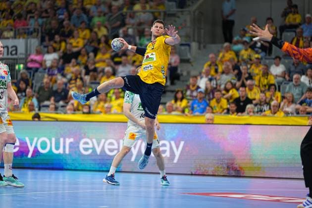Sebastian Heymann 13 Rhein Neckar Löwen jumps up in the SAP Arena and takes a shot while a SC Magdeburg goalkeeper in an orange jersey stretches out his arm In the background are SC Magdeburg players in white jerseys and the packed crowd in the Löwen fan curve Sebastian Heymann 13 Rhein Neckar Löwen taking a jump shot Copyright: xspeedshotx