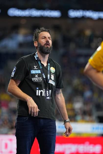 SC Magdeburg coach Bennet Wiegert stands on the touchline in the SAP Arena and looks up with concentration He wears a dark coachs shirt with the logos of SC Magdeburg and DAIKIN HBL as well as an accreditation badge Bennet Wiegert Coach SC Magdeburg follows the action Copyright: xspeedshotx