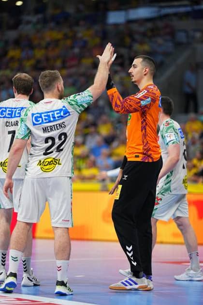 Goalkeeper Matej Mandi 12 SC Magdeburg in orange goalkeeper jersey high-fives with Lukas Mertens 22 SC Magdeburg In the background you can see other Magdeburg outfield players and the yellow-clad spectator stands of the SAP Arena Matej Mandi 12 SC Magdeburg and Lukas Mertens 22 at the high five Copyright: xspeedshotx