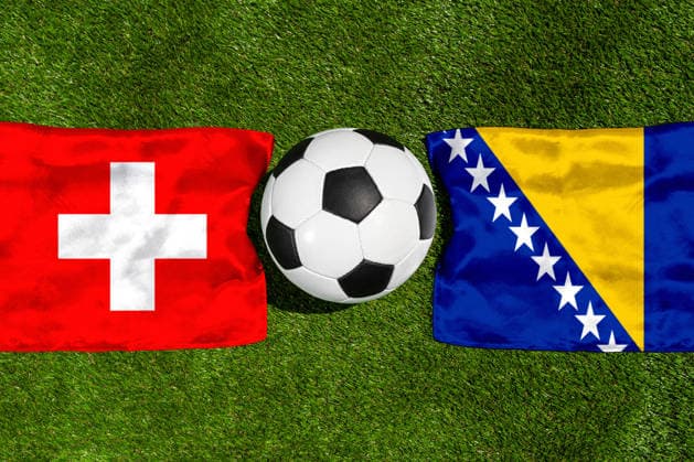 FOTOMONTAGE, Fußball-Weltmeisterschaft 2026: Nationalflaggen von Schweiz und Bosnien Herzegowina mit Fußball auf Rasen. Symbolbild zum WM-Gruppenspiel am 18 Juni bei der FIFA Fussball-Weltmeisterschaft 2026