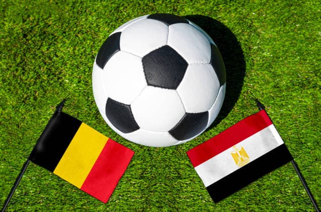 FOTOMONTAGE, Fußball-Weltmeisterschaft 2026: Nationalflaggen von Belgien und Ägypten mit Fußball auf Rasen. Symbolbild zum WM-Gruppenspiel am 15 Juni bei der FIFA Fussball-Weltmeisterschaft 2026