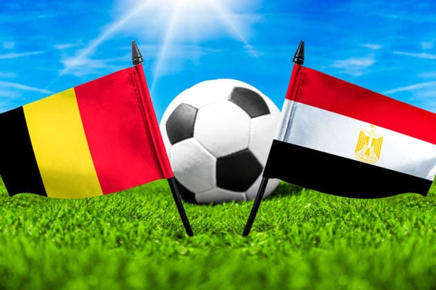 FOTOMONTAGE, Fußball-Weltmeisterschaft 2026: Nationalflaggen von Belgien und Ägypten mit Fußball auf Rasen. Symbolbild zum WM-Gruppenspiel am 15 Juni bei der FIFA Fussball-Weltmeisterschaft 2026