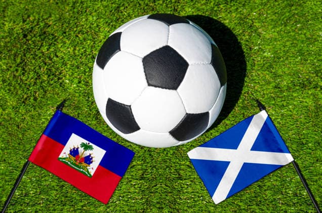 FOTOMONTAGE, Fußball-Weltmeisterschaft 2026: Nationalflaggen von Haiti und Schottland mit Fußball auf Rasen. Symbolbild zum WM-Gruppenspiel am 14 Juni bei der FIFA Fussball-Weltmeisterschaft 2026