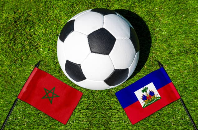FOTOMONTAGE, Fußball-Weltmeisterschaft 2026: Nationalflaggen von Marokko und Haiti mit Fußball auf Rasen. Symbolbild zum WM-Gruppenspiel am 25 Juni bei der FIFA Fussball-Weltmeisterschaft 2026