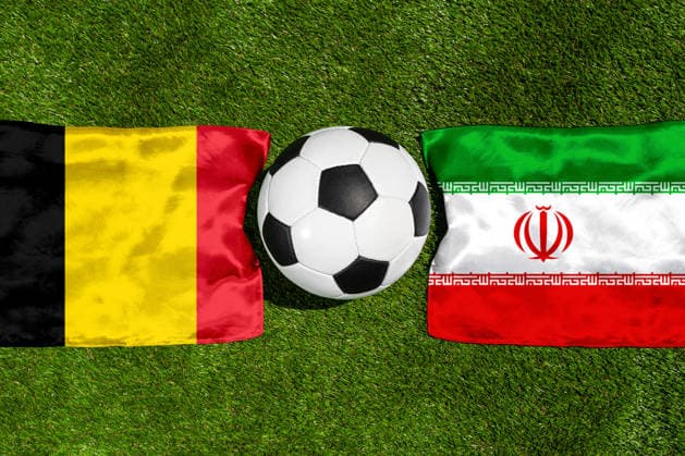 FOTOMONTAGE, Fußball-Weltmeisterschaft 2026: Nationalflaggen von Belgien und Iran mit Fußball auf Rasen. Symbolbild zum WM-Gruppenspiel am 21 Juni bei der FIFA Fussball-Weltmeisterschaft 2026