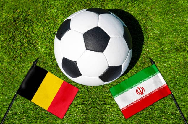 FOTOMONTAGE, Fußball-Weltmeisterschaft 2026: Nationalflaggen von Belgien und Iran mit Fußball auf Rasen. Symbolbild zum WM-Gruppenspiel am 21 Juni bei der FIFA Fussball-Weltmeisterschaft 2026