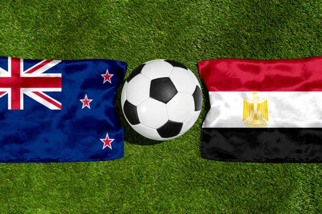 FOTOMONTAGE, Fußball-Weltmeisterschaft 2026: Nationalflaggen von Neuseeland und Ägypten mit Fußball auf Rasen. Symbolbild zum WM-Gruppenspiel am 22 Juni bei der FIFA Fussball-Weltmeisterschaft 2026
