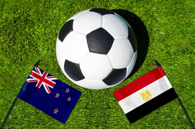 FOTOMONTAGE, Fußball-Weltmeisterschaft 2026: Nationalflaggen von Neuseeland und Ägypten mit Fußball auf Rasen. Symbolbild zum WM-Gruppenspiel am 22 Juni bei der FIFA Fussball-Weltmeisterschaft 2026