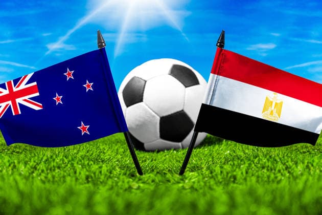FOTOMONTAGE, Fußball-Weltmeisterschaft 2026: Nationalflaggen von Neuseeland und Ägypten mit Fußball auf Rasen. Symbolbild zum WM-Gruppenspiel am 22 Juni bei der FIFA Fussball-Weltmeisterschaft 2026