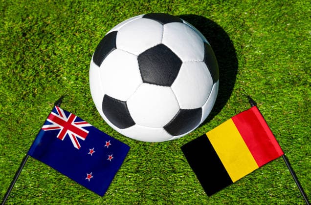 FOTOMONTAGE, Fußball-Weltmeisterschaft 2026: Nationalflaggen von Neuseeland und Belgien mit Fußball auf Rasen. Symbolbild zum WM-Gruppenspiel am 27 Juni bei der FIFA Fussball-Weltmeisterschaft 2026