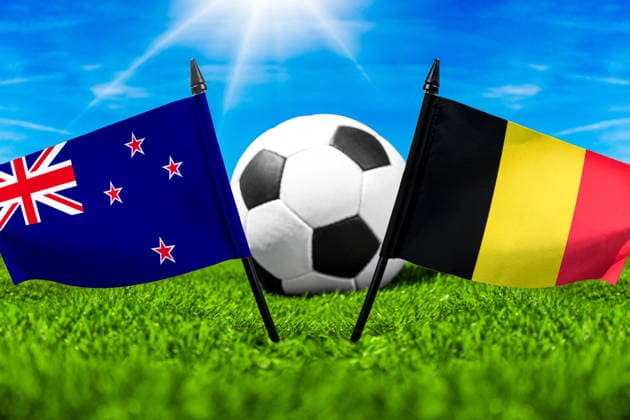 FOTOMONTAGE, Fußball-Weltmeisterschaft 2026: Nationalflaggen von Neuseeland und Belgien mit Fußball auf Rasen. Symbolbild zum WM-Gruppenspiel am 27 Juni bei der FIFA Fussball-Weltmeisterschaft 2026