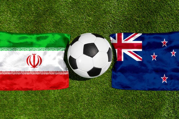FOTOMONTAGE, Fußball-Weltmeisterschaft 2026: Nationalflaggen von Iran und Neuseeland mit Fußball auf Rasen. Symbolbild zum WM-Gruppenspiel am 16 Juni bei der FIFA Fussball-Weltmeisterschaft 2026