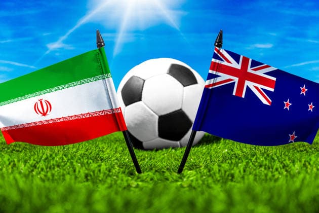 FOTOMONTAGE, Fußball-Weltmeisterschaft 2026: Nationalflaggen von Iran und Neuseeland mit Fußball auf Rasen. Symbolbild zum WM-Gruppenspiel am 16 Juni bei der FIFA Fussball-Weltmeisterschaft 2026