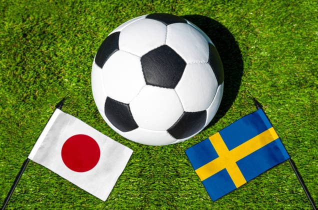 FOTOMONTAGE, Fußball-Weltmeisterschaft 2026: Nationalflaggen von Japan und Schweden mit Fußball auf Rasen. Symbolbild zum WM-Gruppenspiel am 26 Juni bei der FIFA Fussball-Weltmeisterschaft 2026