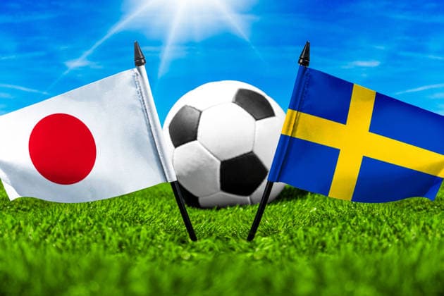 FOTOMONTAGE, Fußball-Weltmeisterschaft 2026: Nationalflaggen von Japan und Schweden mit Fußball auf Rasen. Symbolbild zum WM-Gruppenspiel am 26 Juni bei der FIFA Fussball-Weltmeisterschaft 2026