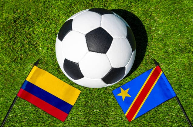 FOTOMONTAGE, Fußball-Weltmeisterschaft 2026: Nationalflaggen von Kolumbien und Kongo mit Fußball auf Rasen. Symbolbild zum WM-Gruppenspiel am 24 Juni bei der FIFA Fussball-Weltmeisterschaft 2026
