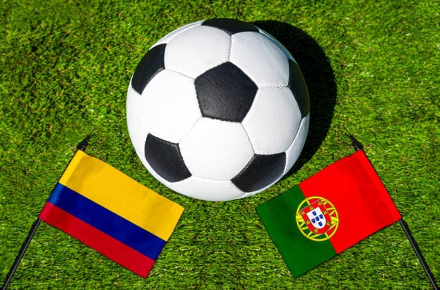 FOTOMONTAGE, Fußball-Weltmeisterschaft 2026: Nationalflaggen von Kolumbien und Portugal mit Fußball auf Rasen. Symbolbild zum WM-Gruppenspiel am 28 Juni bei der FIFA Fussball-Weltmeisterschaft 2026