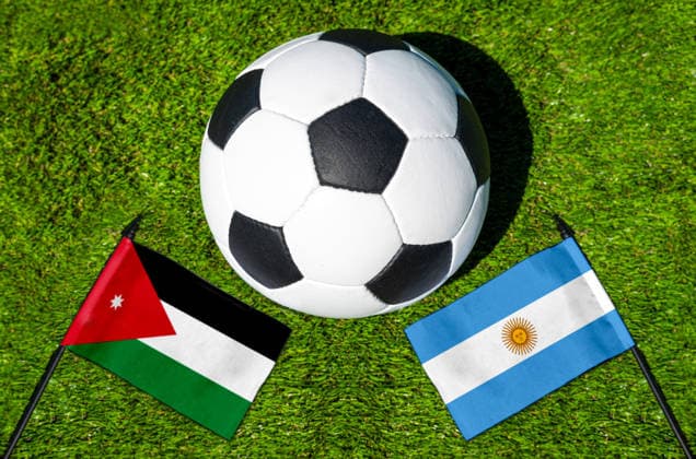 FOTOMONTAGE, Fußball-Weltmeisterschaft 2026: Nationalflaggen von Jordanien und Argentinien mit Fußball auf Rasen. Symbolbild zum WM-Gruppenspiel am 28 Juni bei der FIFA Fussball-Weltmeisterschaft 2026