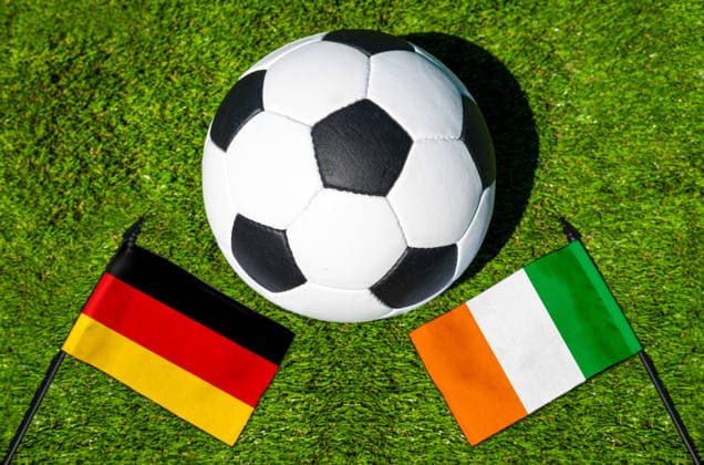 FOTOMONTAGE, Fußball-Weltmeisterschaft 2026: Nationalflaggen von Deutschland und Elfenbeinküste mit Fußball auf Rasen. Symbolbild zum WM-Gruppenspiel am 20 Juni bei der FIFA Fussball-Weltmeisterschaft 2026