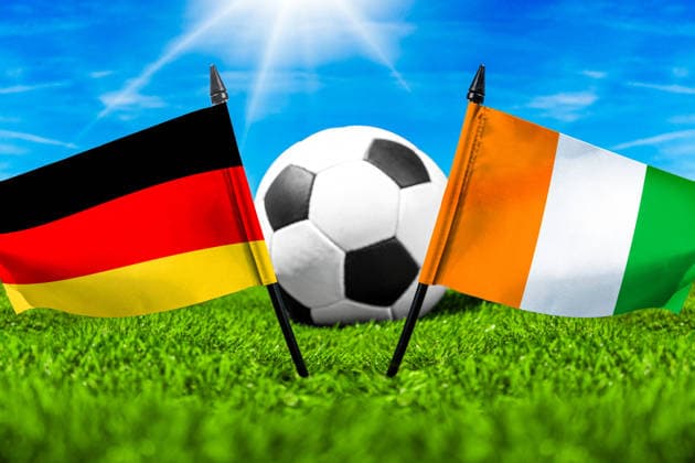 FOTOMONTAGE, Fußball-Weltmeisterschaft 2026: Nationalflaggen von Deutschland und Elfenbeinküste mit Fußball auf Rasen. Symbolbild zum WM-Gruppenspiel am 20 Juni bei der FIFA Fussball-Weltmeisterschaft 2026