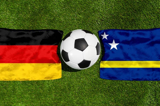 FOTOMONTAGE, Fußball-Weltmeisterschaft 2026: Nationalflaggen von Deutschland und Curacao mit Fußball auf Rasen. Symbolbild zum WM-Gruppenspiel am 14 Juni bei der FIFA Fussball-Weltmeisterschaft 2026