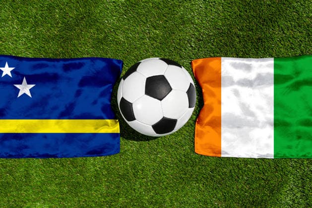 FOTOMONTAGE, Fußball-Weltmeisterschaft 2026: Nationalflaggen von Curacao und Elfenbeinküste mit Fußball auf Rasen. Symbolbild zum WM-Gruppenspiel am 25 Juni bei der FIFA Fussball-Weltmeisterschaft 2026
