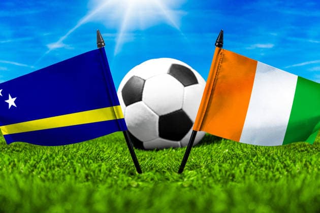 FOTOMONTAGE, Fußball-Weltmeisterschaft 2026: Nationalflaggen von Curacao und Elfenbeinküste mit Fußball auf Rasen. Symbolbild zum WM-Gruppenspiel am 25 Juni bei der FIFA Fussball-Weltmeisterschaft 2026