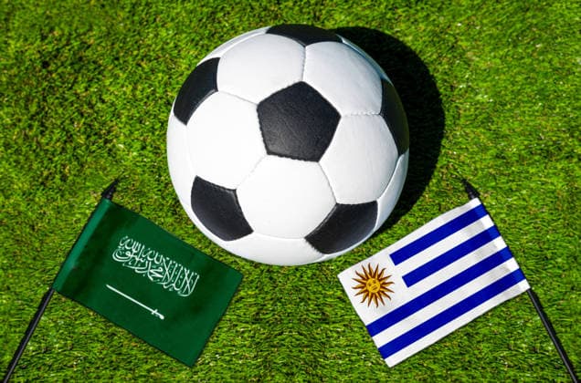 FOTOMONTAGE, Fußball-Weltmeisterschaft 2026: Nationalflaggen von Saudi-Arabien und Uruguay mit Fußball auf Rasen. Symbolbild zum WM-Gruppenspiel am 16 Juni bei der FIFA Fussball-Weltmeisterschaft 2026