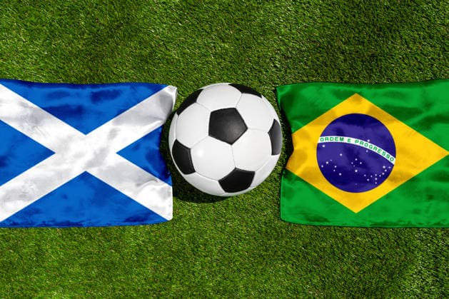 FOTOMONTAGE, Fußball-Weltmeisterschaft 2026: Nationalflaggen von Schottland und Brasilien mit Fußball auf Rasen. Symbolbild zum WM-Gruppenspiel am 25 Juni bei der FIFA Fussball-Weltmeisterschaft 2026