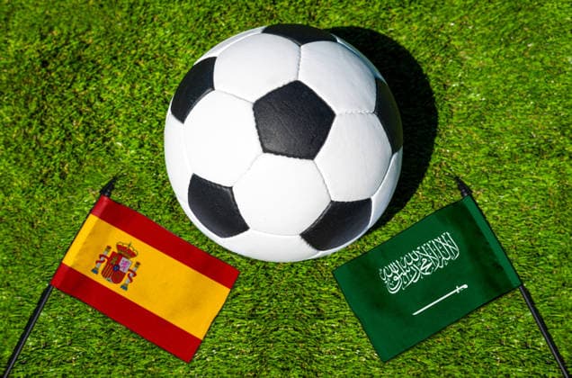 FOTOMONTAGE, Fußball-Weltmeisterschaft 2026: Nationalflaggen von Spanien und Saudi-Arabien mit Fußball auf Rasen. Symbolbild zum WM-Gruppenspiel am 21 Juni bei der FIFA Fussball-Weltmeisterschaft 2026