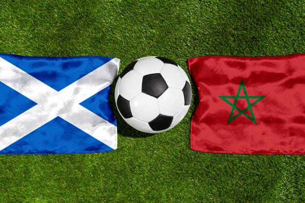 FOTOMONTAGE, Fußball-Weltmeisterschaft 2026: Nationalflaggen von Schottland und Marokko mit Fußball auf Rasen. Symbolbild zum WM-Gruppenspiel am 20 Juni bei der FIFA Fussball-Weltmeisterschaft 2026