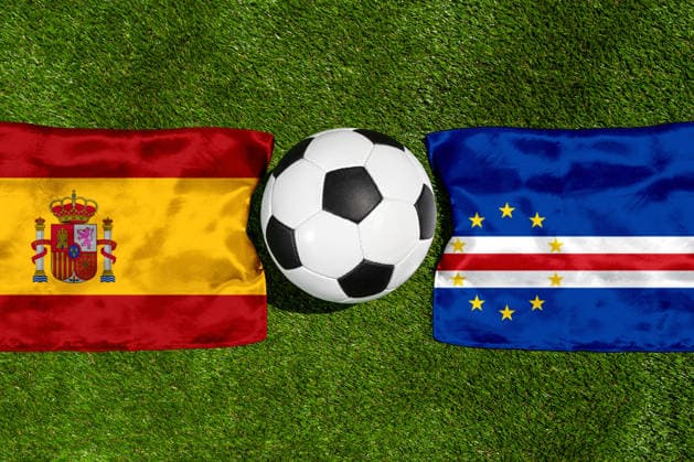 FOTOMONTAGE, Fußball-Weltmeisterschaft 2026: Nationalflaggen von Spanien und Kap Verde mit Fußball auf Rasen. Symbolbild zum WM-Gruppenspiel am 15 Juni bei der FIFA Fussball-Weltmeisterschaft 2026