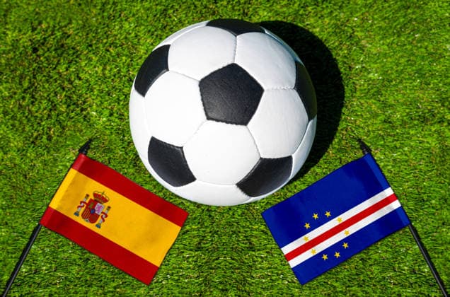 FOTOMONTAGE, Fußball-Weltmeisterschaft 2026: Nationalflaggen von Spanien und Kap Verde mit Fußball auf Rasen. Symbolbild zum WM-Gruppenspiel am 15 Juni bei der FIFA Fussball-Weltmeisterschaft 2026