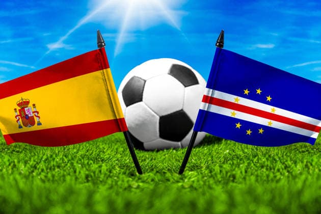 FOTOMONTAGE, Fußball-Weltmeisterschaft 2026: Nationalflaggen von Spanien und Kap Verde mit Fußball auf Rasen. Symbolbild zum WM-Gruppenspiel am 15 Juni bei der FIFA Fussball-Weltmeisterschaft 2026