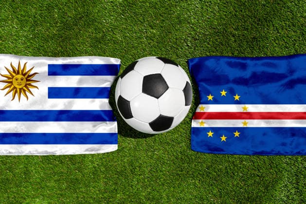 FOTOMONTAGE, Fußball-Weltmeisterschaft 2026: Nationalflaggen von Uruguay und Kap Verde mit Fußball auf Rasen. Symbolbild zum WM-Gruppenspiel am 22 Juni bei der FIFA Fussball-Weltmeisterschaft 2026