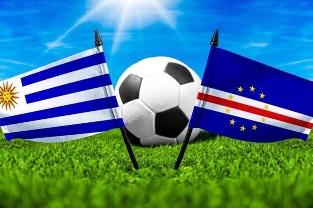 FOTOMONTAGE, Fußball-Weltmeisterschaft 2026: Nationalflaggen von Uruguay und Kap Verde mit Fußball auf Rasen. Symbolbild zum WM-Gruppenspiel am 22 Juni bei der FIFA Fussball-Weltmeisterschaft 2026