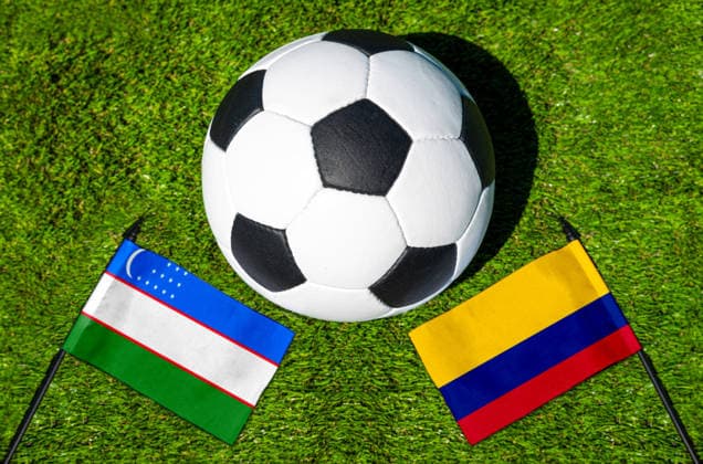 FOTOMONTAGE, Fußball-Weltmeisterschaft 2026: Nationalflaggen von Usbekistan und Kolumbien mit Fußball auf Rasen. Symbolbild zum WM-Gruppenspiel am 18 Juni bei der FIFA Fussball-Weltmeisterschaft 2026