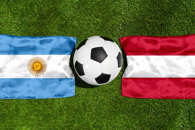 FOTOMONTAGE, Fußball-Weltmeisterschaft 2026: Nationalflaggen von Argentinien und Österreich mit Fußball auf Rasen. Symbolbild zum WM-Gruppenspiel am 22 Juni bei der FIFA Fussball-Weltmeisterschaft 2026