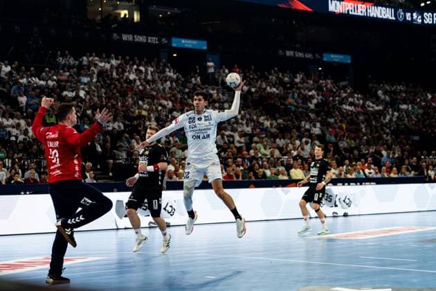 Benjamin Richert 22 Montpellier HB jumps up and takes a shot while SG Flensburg Handewitt players try to block the shot The packed arena with the Montpellier Handball vs SG scoreboard can be seen in the background Benjamin Richert 22 Montpellier HB taking a jump shot against SG Flensburg Handewitt Copyright: xPhilippHeistx