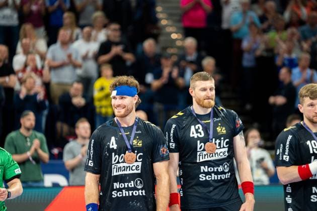 Johannes Golla 3 SG Flensburg Handewitt and Blaž Blagotinöek 43 SG Flensburg Handewitt stand smiling with bronze medals around their necks in front of applauding spectators Both wear the black jersey of SG Flensburg Handewitt Johannes Golla 3 SG Flensburg Handewitt and Blaž Blagotinöek 43 SG Flensburg Handewitt with bronze medal Copyright: xPhilippHeistx