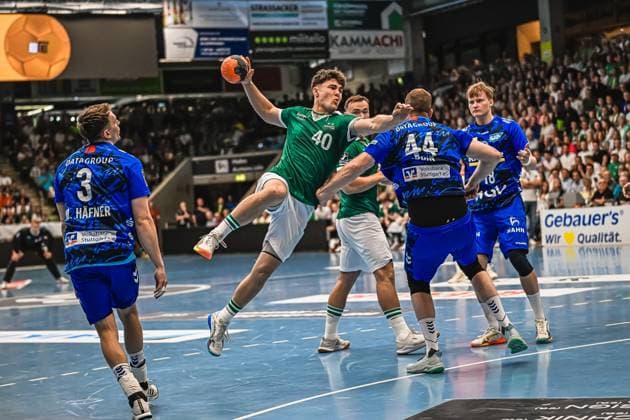 A player from Frisch Auf Göppingen 40 jumps to shoot and is harassed by several TVB Stuttgart opponents In the background you can see the well-filled hall Player 40 Frisch Auf Göppingen taking a jump shot against TVB Stuttgart Copyright: xspeedshotx xDorianfrickx