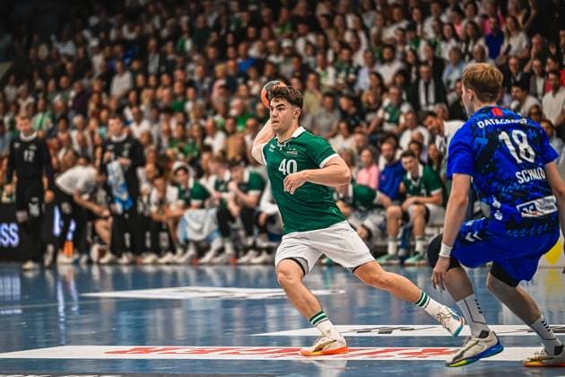 A player from Frisch Auf Göppingen 40 takes a shot with the ball while a player from TVB Stuttgart 18 stands in defense The game takes place in front of a sold-out crowd Frisch Auf Göppingen player 40 attempting a shot against TVB Stuttgart Copyright: xspeedshotx xDorianfrickx