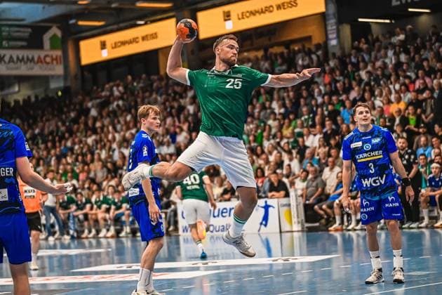 A Frisch Auf Göppingen player jumps with the ball to shoot and pulls high into the air Several TVB Stuttgart players watch the action from the defense Player 25 Frisch Auf Göppingen taking a jump shot against TVB Stuttgart Copyright: xspeedshotx xDorianfrickx