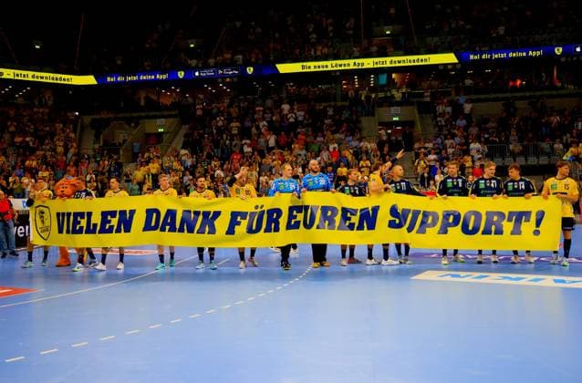The Rhein Neckar Löwen team stands together on the pitch and holds up a large yellow banner with the inscription Thank you for your support . Recognizable are Dani Baijens 77 Rhein Neckar Löwen , David Möré 15 Rhein Neckar Löwen , Lukas Sandell 11 Rhein Neckar Löwen and Tim Nothdurft 8 Rhein Neckar Löwen Rhein Neckar Löwen thank fans with banner after the end of the match Copyright: xspeedshotx