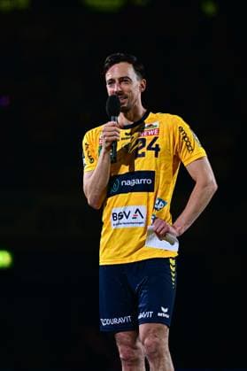 Patrick Groetzki 24 Rhein Neckar Löwen stands in a players jersey with a microphone in his hand in front of a dark background He holds a sheet of paper in his other hand and speaks to the audience Patrick Groetzki 24 Rhein Neckar Löwen speaks into the microphone Copyright: xMichaelxGelhardtx